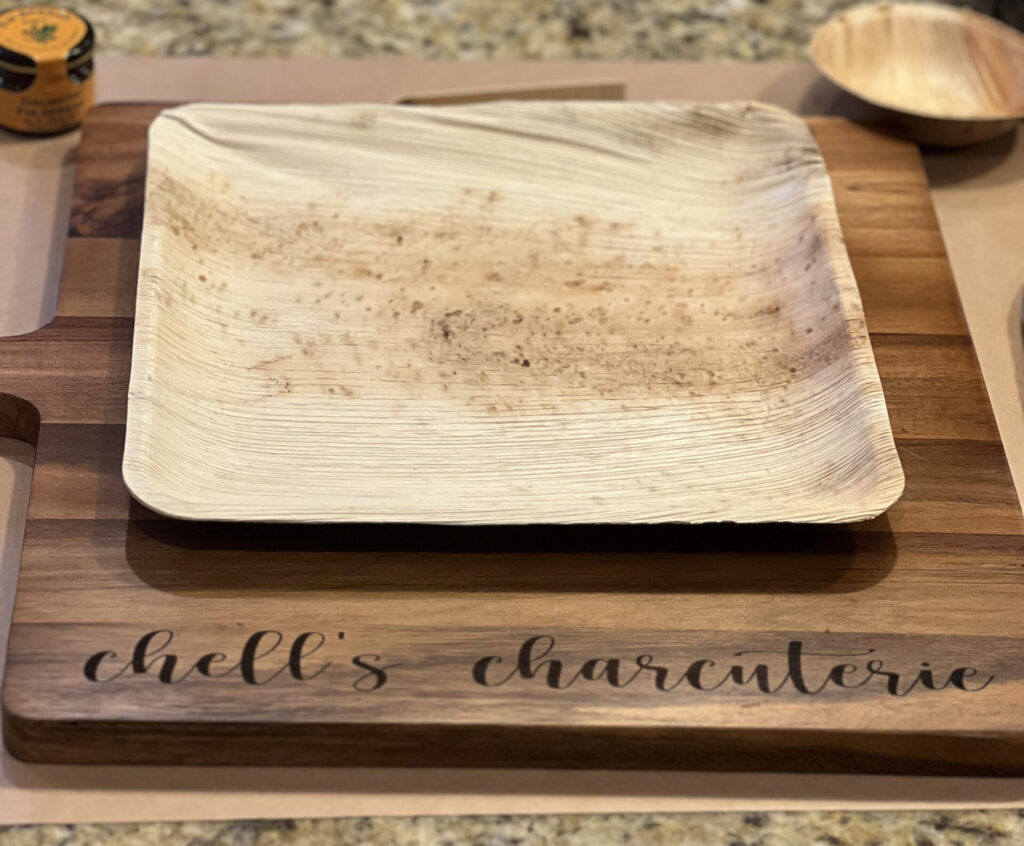 An empty plate on top of a beautiful Chelle's Charcuterie cutting board. Ready for you to build your board!