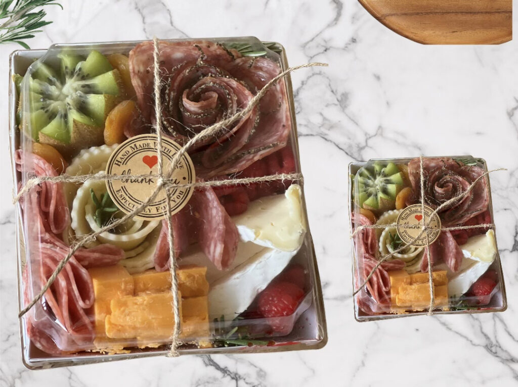 Individual bite boxes of charcuterie, on top of a marble background