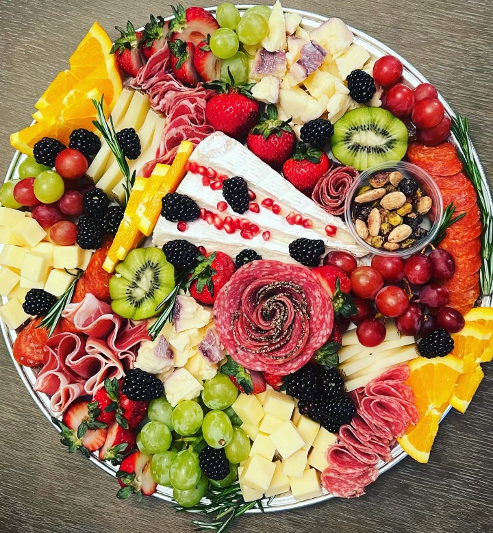 A colorful, custom-made charcuterie board on a circular metal tray.